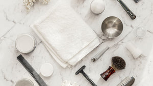 array of shaving accessories on a white granite countertop