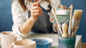 a woman paints pottery